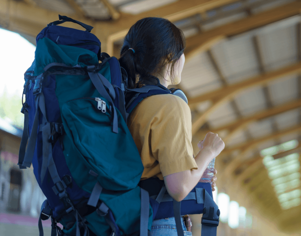 Kvinna som väntar på en tågstation med en ryggsäck på ryggen