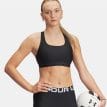en modell bär en svart Under Armour Cross Back Mid Bra sport-bh (dam)