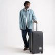 person som håller i Herschel Heritage Hardshell Medium Luggage 67 L resväska (unisex)